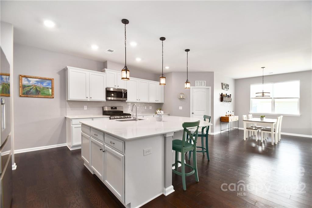 17239 Shearer Road Davidson, NC 28036 - Photo 7 of 32 a kitchen with stainless steel appliances kitchen island granite countertop a stove a sink a dining table and chairs with wooden floor