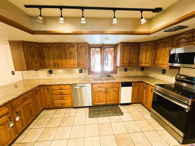 a view of a kitchen with kitchen island granite countertop a sink and wooden cabinets