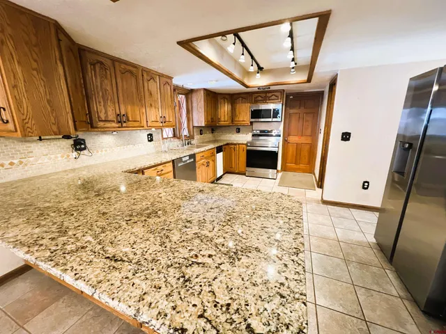 a large kitchen with a stove a refrigerator a sink dishwasher with a dining table and chairs