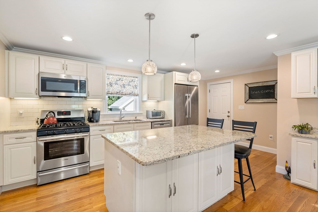 105 Brewster Road Waltham, MA 02451 - Photo 7 of 32 a kitchen with kitchen island a stove a sink a microwave and wooden cabinets