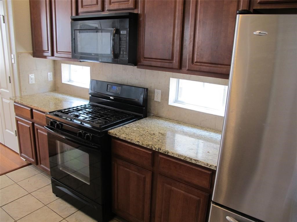 6715 Windrift Way, Unit 15 Austin, TX 78745 - Photo 10 of 37 a kitchen with granite countertop wood cabinets and a stove top oven