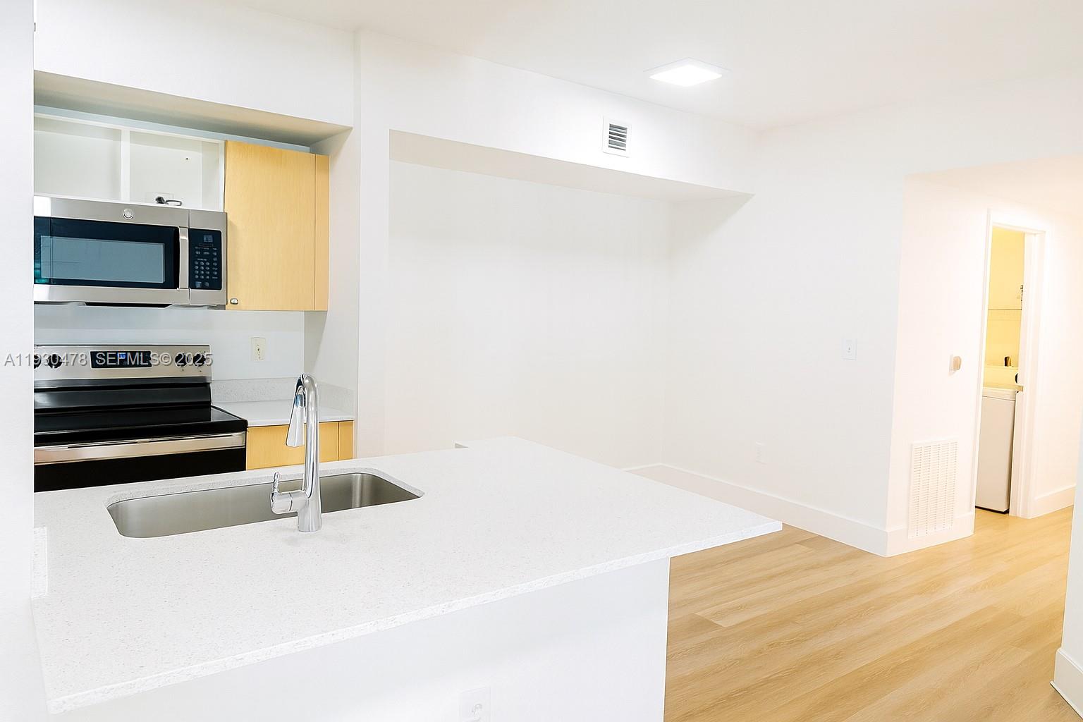 2564 Centergate Drive, Unit 208 Miramar, FL 33025 - Photo 20 of 31 a kitchen with granite countertop a sink and a stove top oven