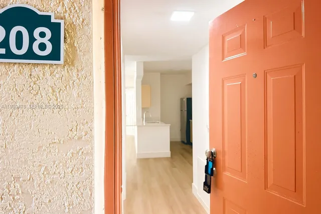 a view of a hallway with wooden floor and a bathroom