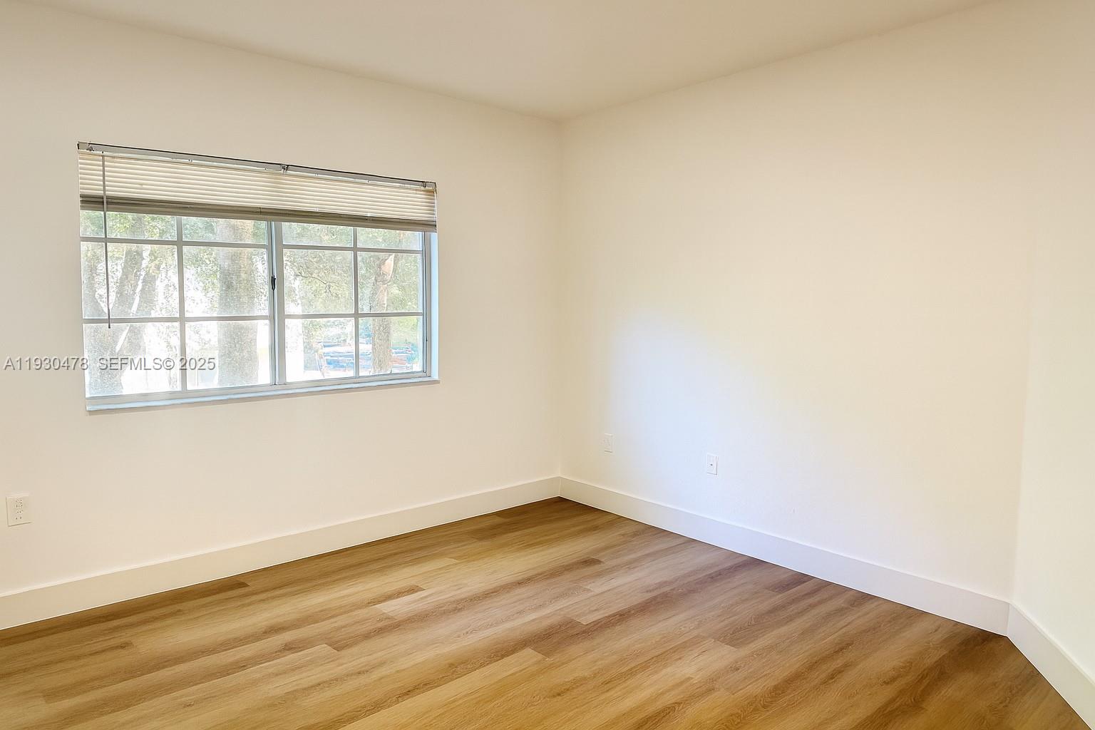 2564 Centergate Drive, Unit 208 Miramar, FL 33025 - Photo 3 of 31 a view of an empty room with wooden floor and a window