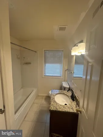 a bathroom with a granite countertop sink mirror vanity and bathtub