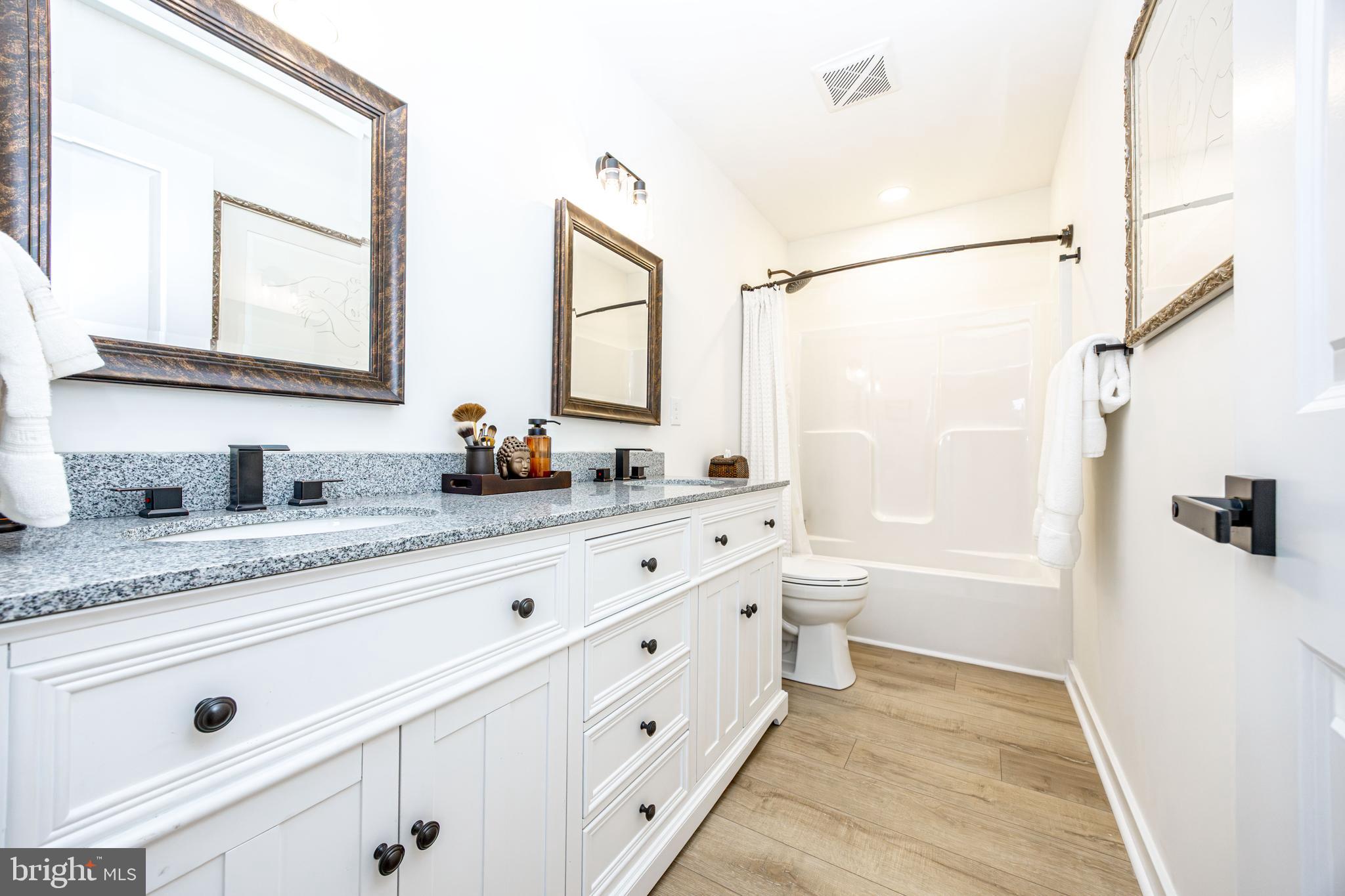 1117 Chester Road Middle River, MD 21220 - Photo 50 of 95 a bathroom with a granite countertop sink a mirror a bathtub and a shower