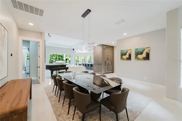 a kitchen with stainless steel appliances kitchen island granite countertop a dining table chairs and a refrigerator