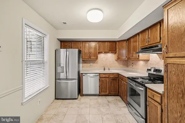 a kitchen with stainless steel appliances granite countertop a refrigerator stove top oven a sink and dishwasher