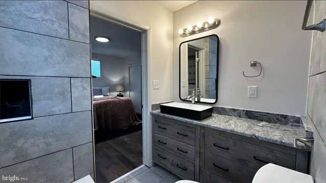 a en suite bathroom with a granite countertop sink and a mirror