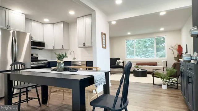 a kitchen with stainless steel appliances granite countertop a stove a refrigerator a sink a dining table and chairs