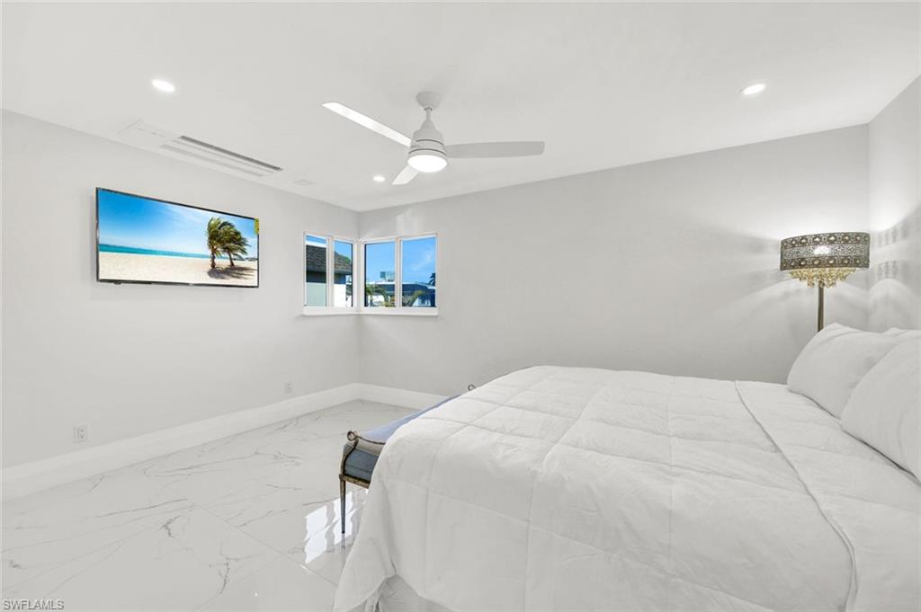 20 Kings Road, Unit A18 Naples, FL 34112 - Photo 12 of 19 a bedroom with a large bed and a chandelier