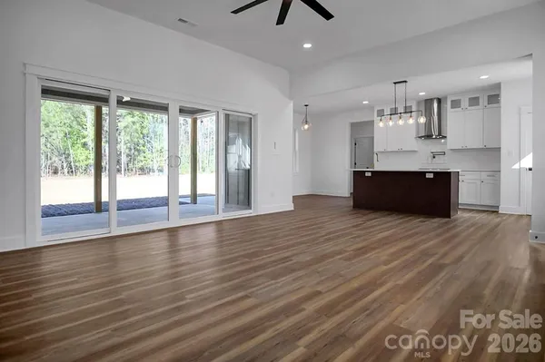 a kitchen with stainless steel appliances granite countertop a stove a sink and white cabinets with wooden floor