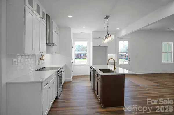 a kitchen with granite countertop a sink stove and refrigerator