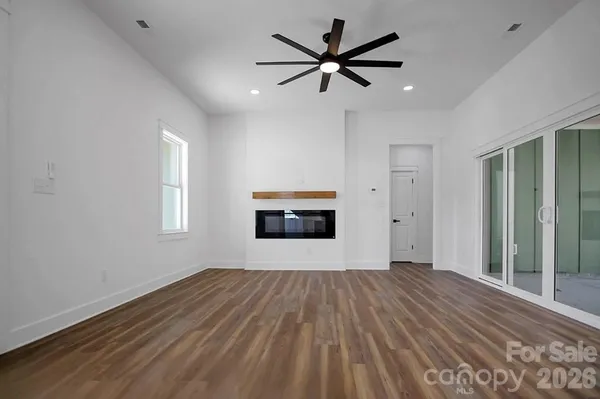 an empty room with wooden floor a ceiling fan and windows