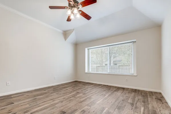 an empty room with wooden floor chandelier fan and windows