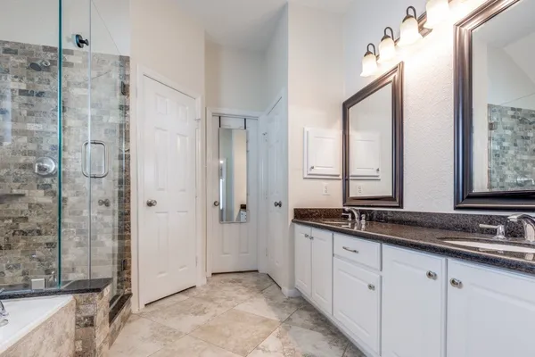 a bathroom with a granite countertop sink two mirror and a shower