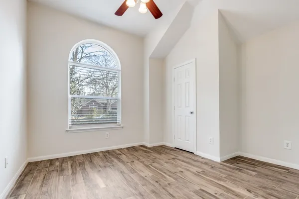 an empty room with wooden floor closet and windows