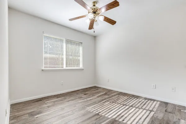an empty room with a window and a ceiling fan