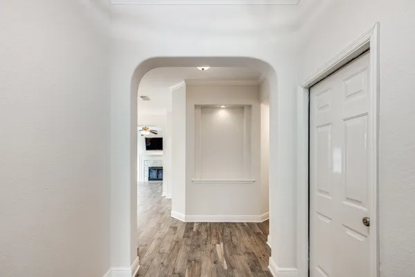 a view of a hallway with wooden floor and a bathroom