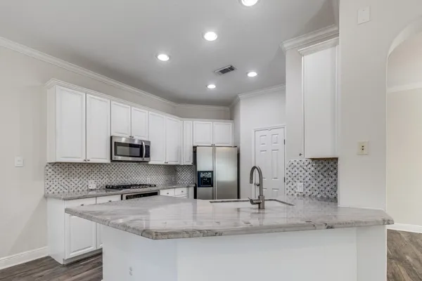 a kitchen with kitchen island granite countertop a sink a stove and refrigerator