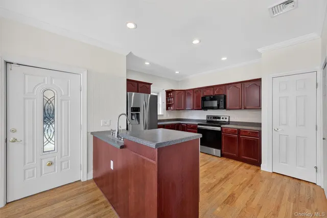 a kitchen with stainless steel appliances granite countertop a stove top oven a sink dishwasher a refrigerator and a dining table with wooden floor