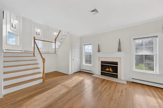 a view of an empty room with wooden floor fireplace and a window