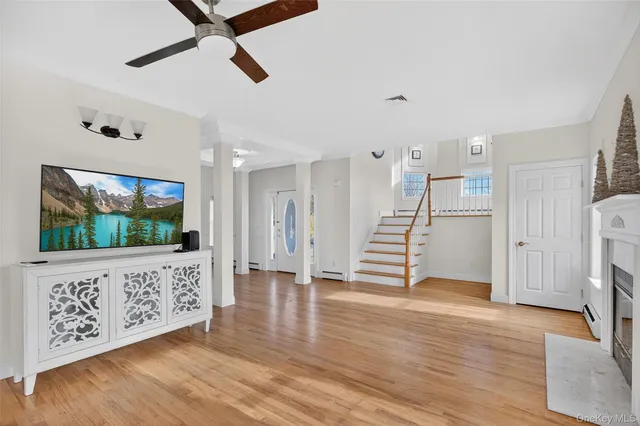 a view of an empty room with wooden floor and a ceiling fan