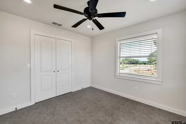 a view of a livingroom with a ceiling fan & windows
