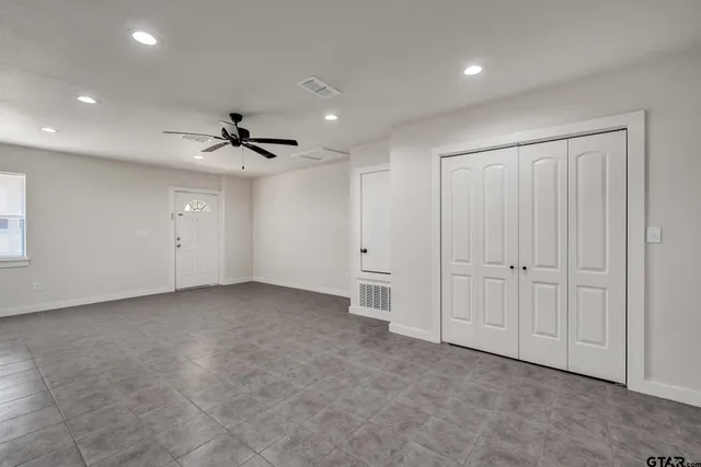 an empty room with fan and windows