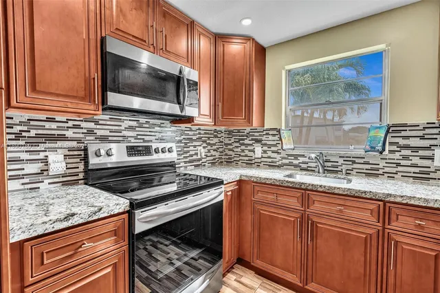 a kitchen with granite countertop a stove sink and microwave