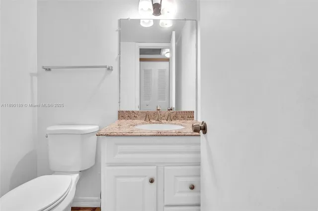 a bathroom with a granite countertop toilet sink and mirror