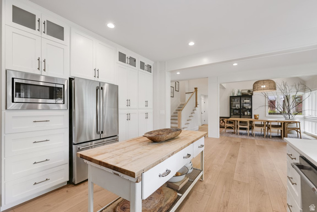 180 Farm Road Midway, UT 84049 - Photo 35 of 99 Chef's kitchen featuring white cabinetry with brushed nickel hardware, stainless steel appliances including a built-in microwave and refrigerator, a wood-top island with storage drawers, and wood-finish flooring throughout