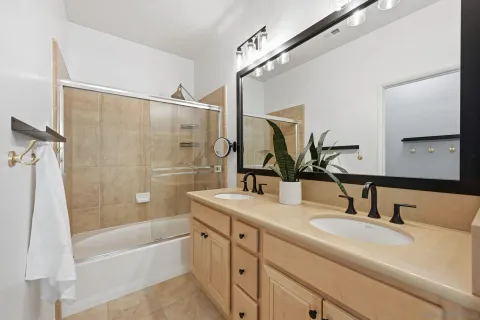 a bathroom with a tub sink vanity granite and mirror