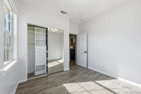 a view of an empty room with wooden floor and closet