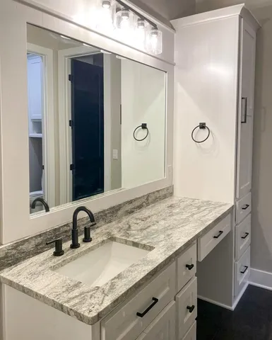 a bathroom with a granite countertop sink and a mirror