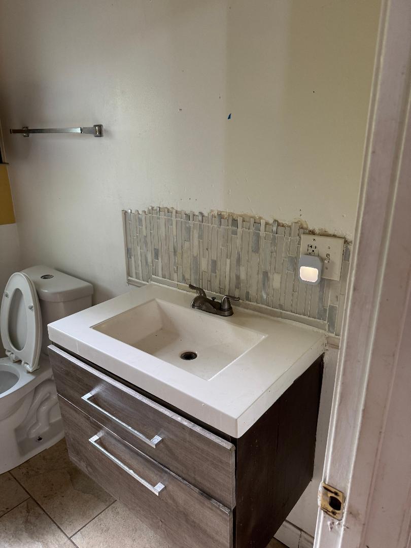 10200 South Rhodes Avenue Chicago, IL 60628 - Photo 13 of 22 a bathroom with a sink a toilet and mirror