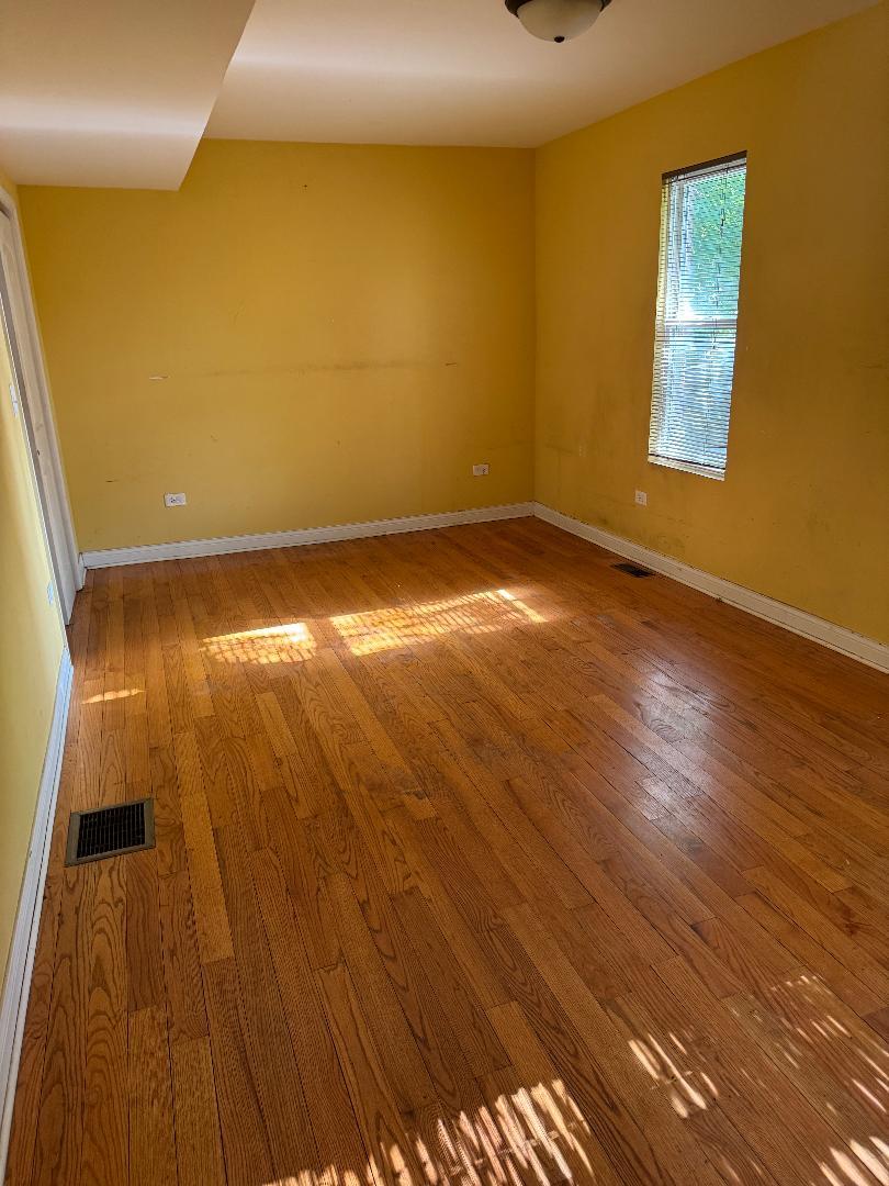10200 South Rhodes Avenue Chicago, IL 60628 - Photo 8 of 22 a view of an empty room with wooden floor and a window