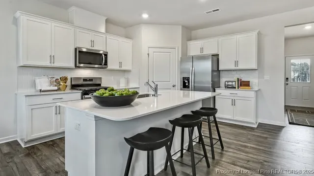 a kitchen with stainless steel appliances a sink a stove a refrigerator cabinets and wooden floor