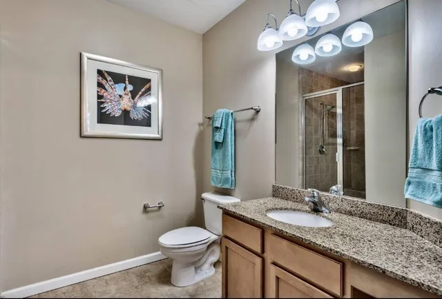 a bathroom with a granite countertop sink a toilet and a mirror