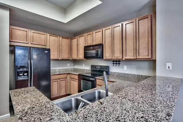 a kitchen with stainless steel appliances granite countertop a refrigerator a stove top oven a sink and dishwasher