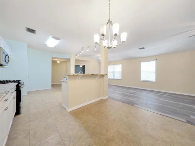 an empty room with chandelier fan and windows