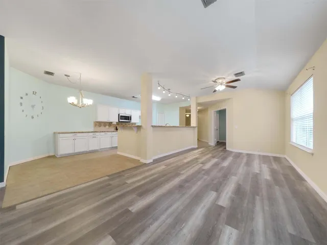 a view of an empty room and kitchen view