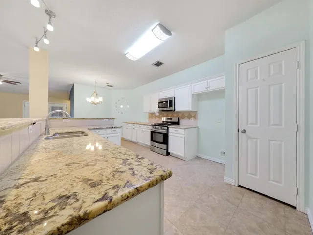 a large kitchen with stainless steel appliances granite countertop a sink and cabinets