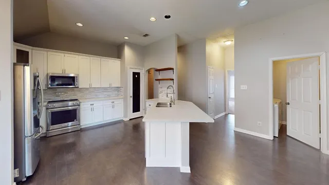 a kitchen with stainless steel appliances a stove top oven a sink refrigerator and cabinets