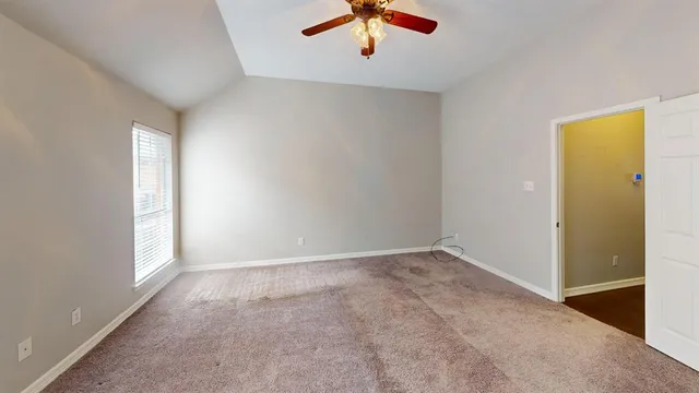 an empty room with windows and ceiling fan view