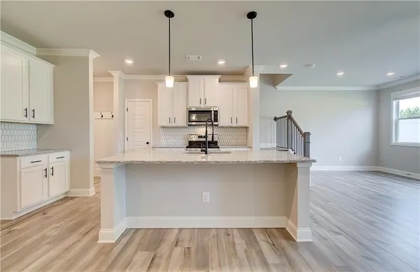 a view of a kitchen with kitchen island a sink stainless steel appliances and cabinets