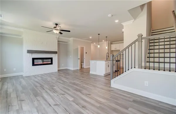 a view of an empty room with wooden floor and a ceiling fan