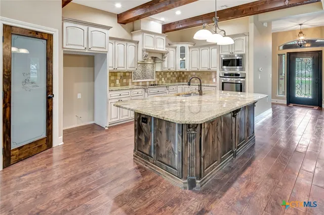 a kitchen with stainless steel appliances granite countertop a kitchen island a hardwood floor and a view of living room