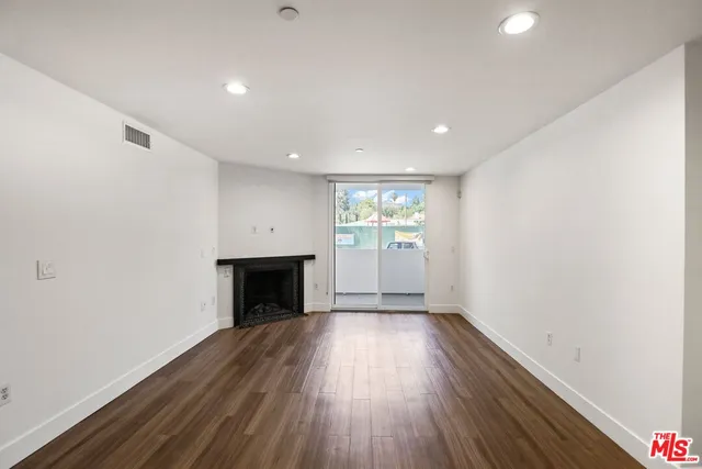 an empty room with a fireplace and wooden floor