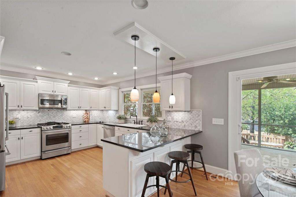 1435 Lilac Road Charlotte, NC 28209 - Photo 12 of 33 a kitchen with kitchen island granite countertop wooden floors and white cabinets